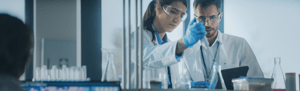 A woman and a man, both scientists, at work in a laboratory analyzing samples.